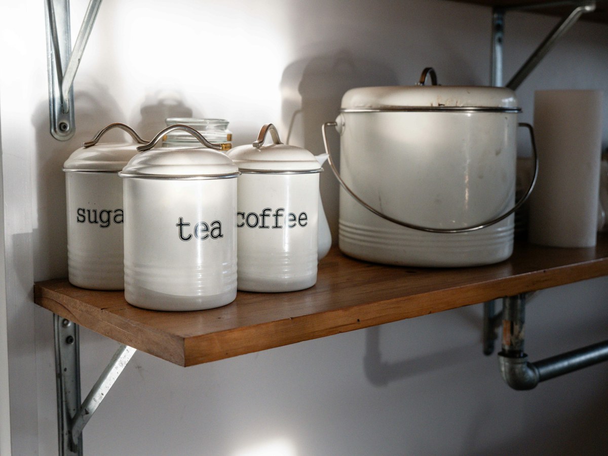 White canisters labeled sugar, tea, and coffee on shelf